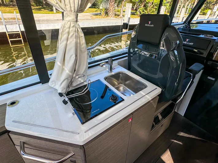  Yacht Photos Pics 2025 Wellcraft 355 boat interior with kitchenette and captain's chair.