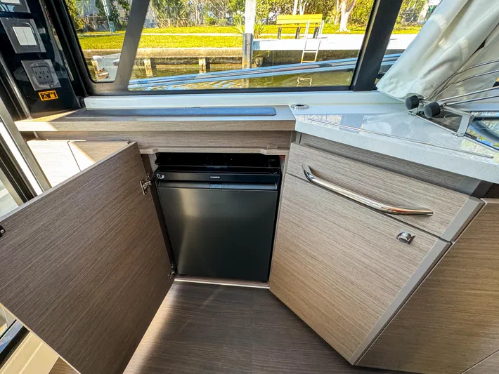  Yacht Photos Pics 2025 Wellcraft 355 interior with open cabinet and mini fridge.