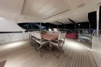 Luxurious 2018 Benetti 95 Delfino yacht deck with elegant dining area at night.