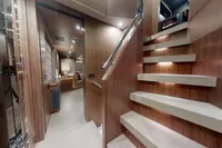 Luxurious interior of 2018 Benetti 95 Delfino yacht with modern staircase and elegant wood finishes.