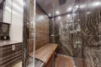 Luxurious bathroom with marble walls and wooden accents on a 2018 Benetti 95 Delfino yacht.