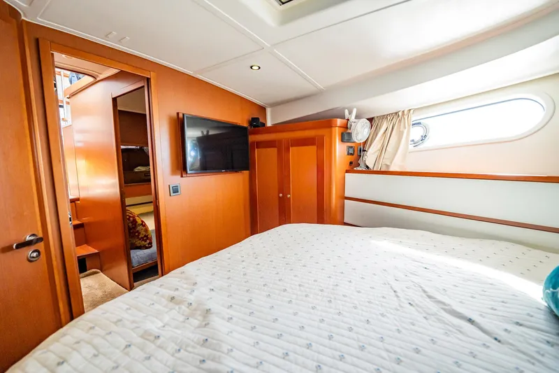 Wanderer Yacht Photos Pics 2016 Beneteau Swift Trawler 44 cabin interior with bed, TV, and wooden furnishings.