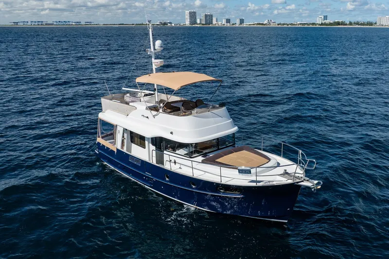 Wanderer Yacht Photos Pics 2016 Beneteau Swift Trawler 44 cruising on open water, city skyline in background.