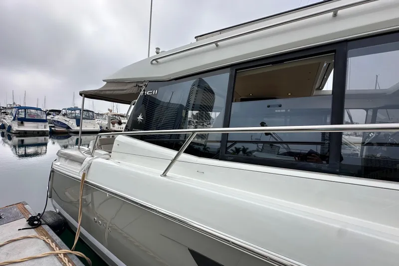  Yacht Photos Pics 2015 Jeanneau NC11 yacht docked at marina, side view with reflections on water.