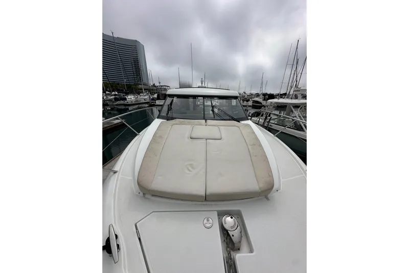  Yacht Photos Pics 2015 Jeanneau NC11 yacht with cushioned deck, docked in a marina under cloudy skies.