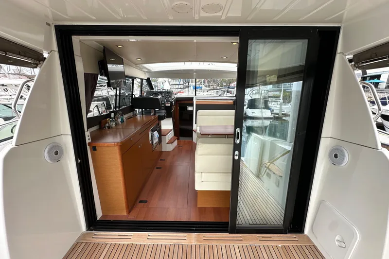  Yacht Photos Pics Interior view of 2015 Jeanneau NC11 yacht with modern furnishings and sliding glass door.
