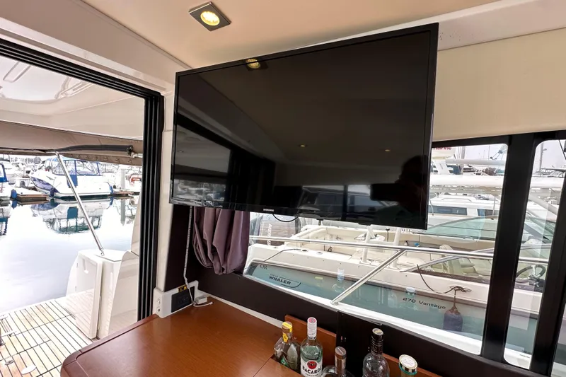  Yacht Photos Pics Interior of 2015 Jeanneau NC11 yacht with TV and bar setup, overlooking marina.