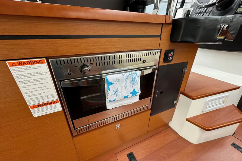  Yacht Photos Pics 2015 Jeanneau NC11 interior with wooden cabinetry and built-in oven.