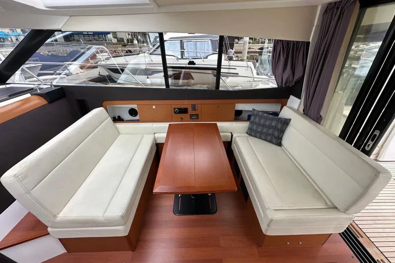  Yacht Photos Pics Interior of 2015 Jeanneau NC11 yacht with elegant seating and wooden table.