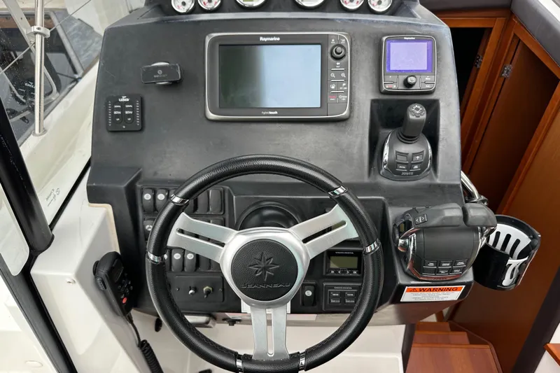  Yacht Photos Pics Control panel of a 2015 Jeanneau NC11 boat with steering wheel and navigation equipment.