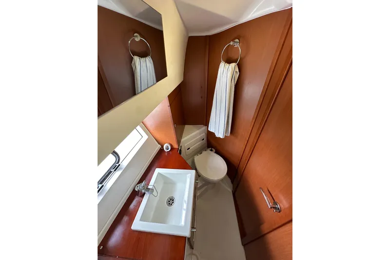  Yacht Photos Pics 2015 Jeanneau NC11 bathroom with sink, mirror, and wooden cabinetry.