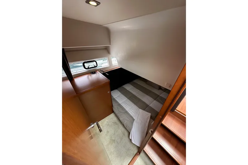  Yacht Photos Pics Cozy cabin interior of 2015 Jeanneau NC11 boat with bed and wooden furnishings.