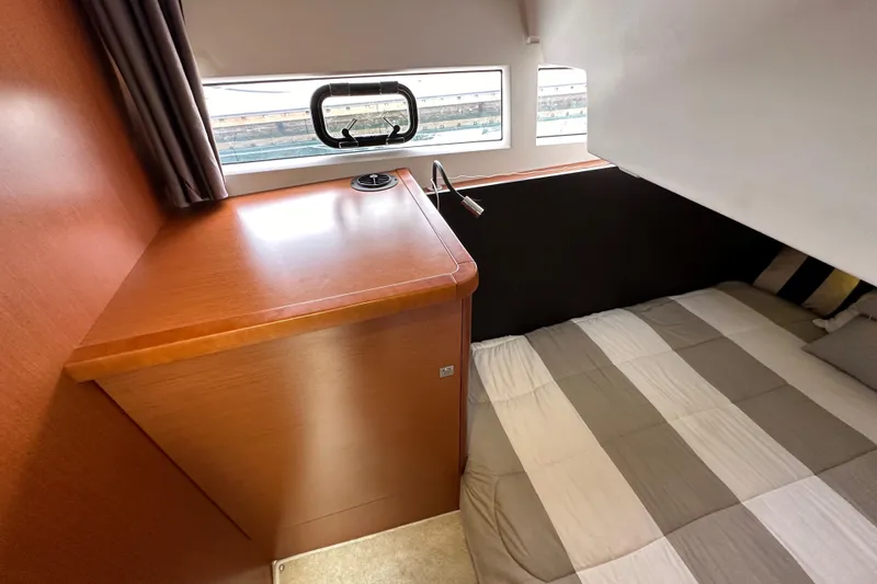  Yacht Photos Pics 2015 Jeanneau NC11 cabin interior with bed, wooden cabinetry, and window.