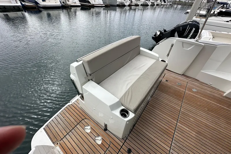 Yacht Photos Pics 2015 Jeanneau NC11 boat with cushioned seating on teak deck at marina.