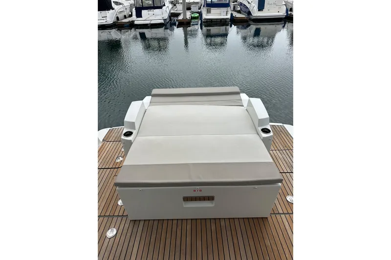  Yacht Photos Pics 2015 Jeanneau NC11 yacht with cushioned sunbed on teak deck, docked at marina.