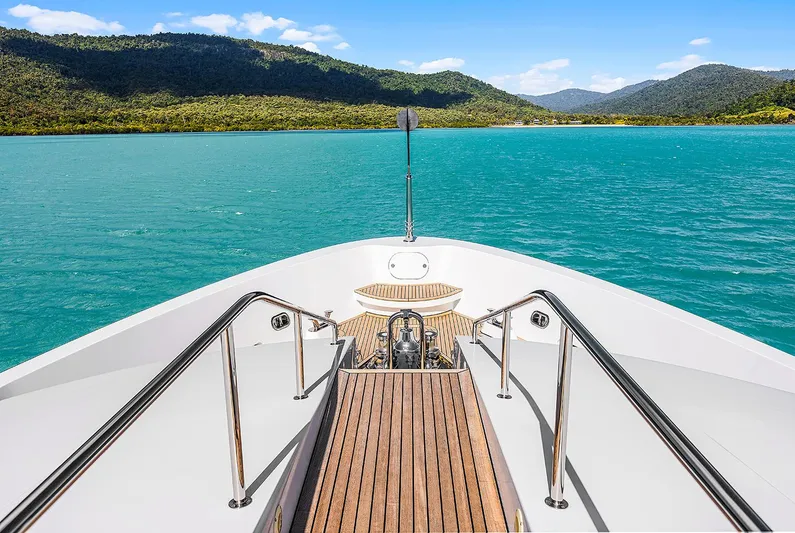  Yacht Photos Pics Bow view of 2003 Sovereign Tri-Deck yacht on turquoise water, surrounded by lush mountains.