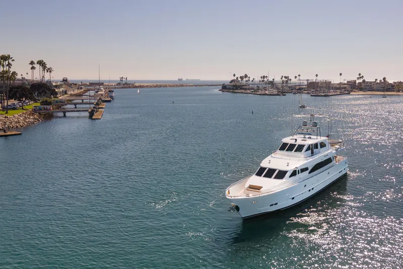 Reverie Yacht Photos Pics Luxury yacht cruising in a sunny marina, surrounded by calm waters and palm trees.