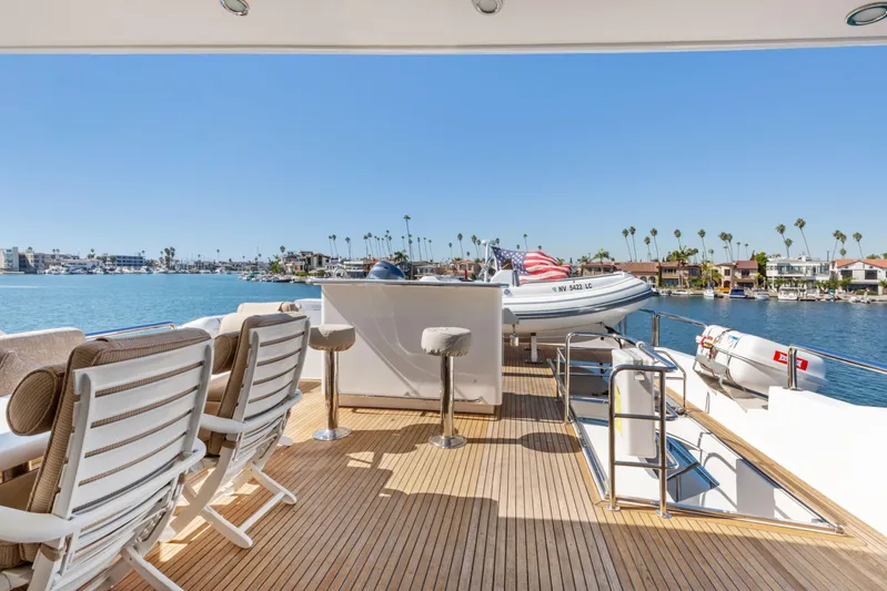 Reverie Yacht Photos Pics Luxury yacht deck with seating, bar stools, and scenic waterfront view.