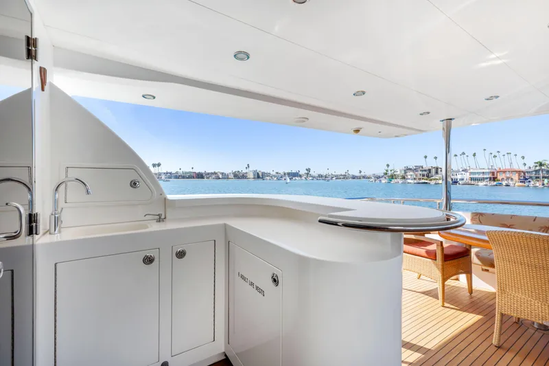 Reverie Yacht Photos Pics Luxurious yacht deck with bar and seating, overlooking scenic waterfront view.