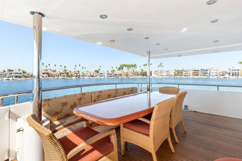 Reverie Yacht Photos Pics Luxurious yacht deck with wicker furniture, overlooking a scenic waterfront view.