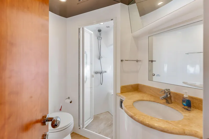 Reverie Yacht Photos Pics Compact yacht bathroom with shower, sink, and toilet, featuring modern fixtures and wooden accents.
