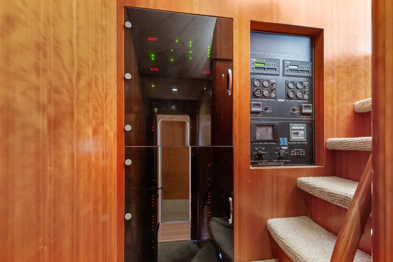 Reverie Yacht Photos Pics Control panel and staircase in a 2005 Custom model interior, featuring wood paneling and carpeted steps.
