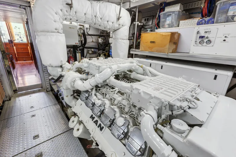 Reverie Yacht Photos Pics Engine room with a 2005 Custom MAN engine, featuring metallic flooring and control panels.