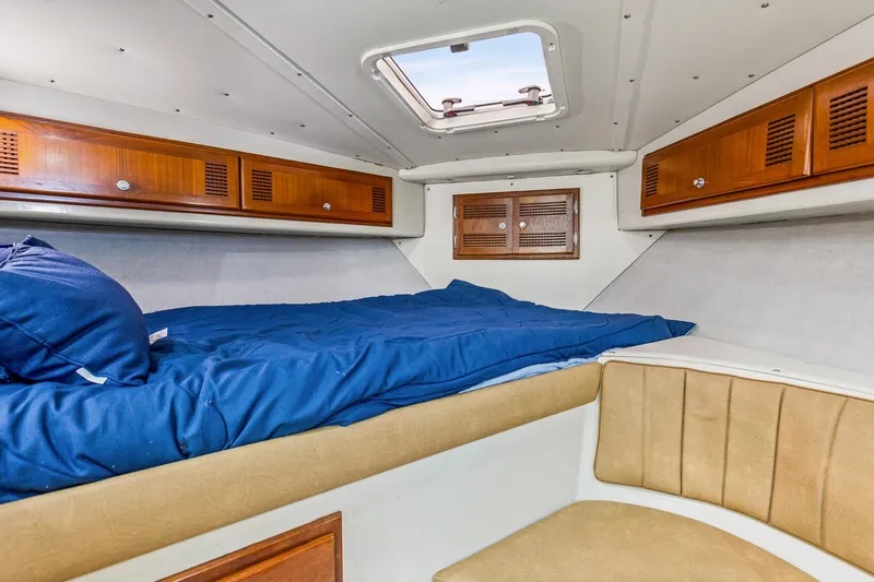 2017 Cummins 540s And Major Re-fit Throughout Yacht Photos Pics 1995 Cabo 35 Express cabin interior with blue bedding and wooden storage cabinets.