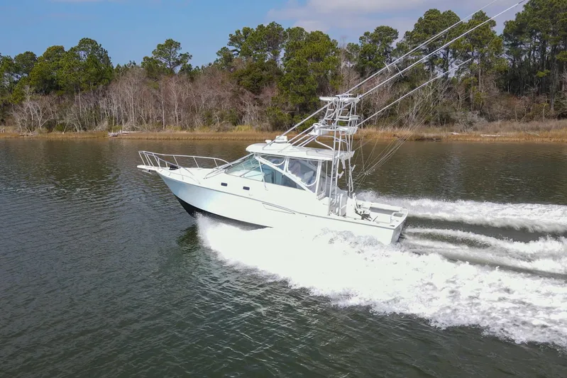 2017 Cummins 540s And Major Re-fit Throughout Yacht Photos Pics 1995 Cabo 35 Express boat cruising on a calm lake with trees in the background.
