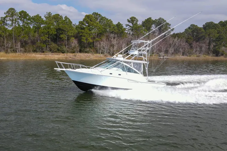 2017 Cummins 540s And Major Re-fit Throughout Yacht Photos Pics 1995 Cabo 35 Express boat cruising on a scenic waterway with lush forest backdrop.