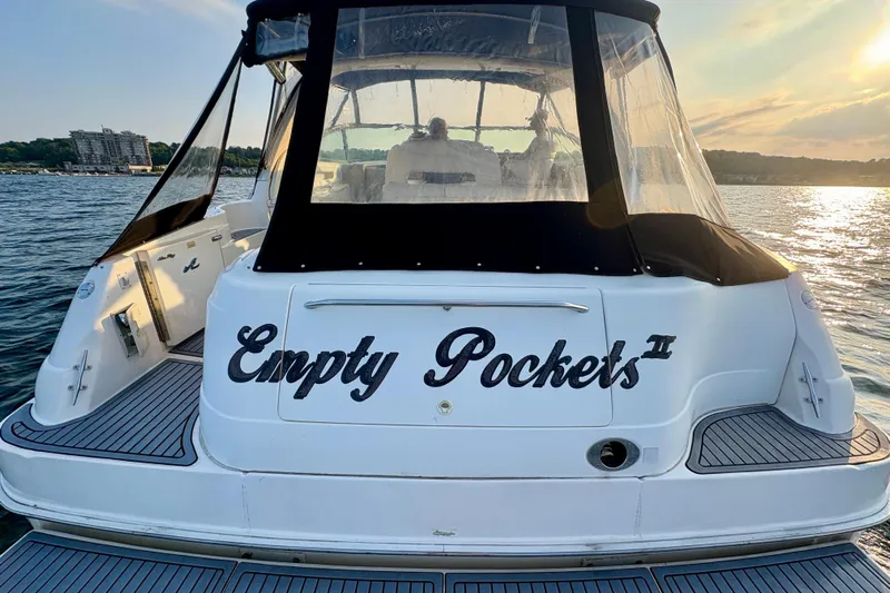 Empty Pockets Yacht Photos Pics 1999 Sea Ray 460 Sundancer yacht named "Empty Pockets II" on serene water at sunset.