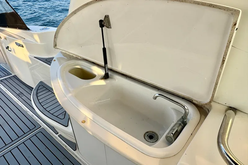 Empty Pockets Yacht Photos Pics 1999 Sea Ray 460 Sundancer yacht sink area with open lid, docked by the water.