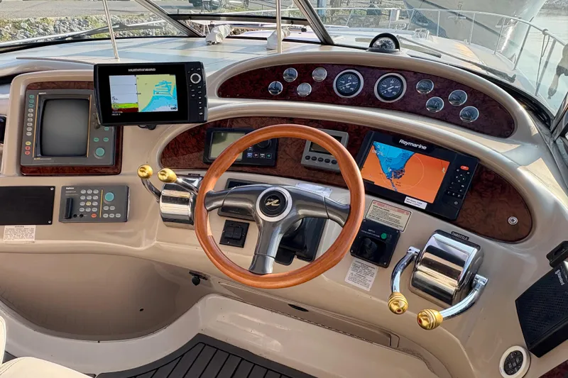 Empty Pockets Yacht Photos Pics Cockpit of 1999 Sea Ray 460 Sundancer with navigation equipment and wooden steering wheel.