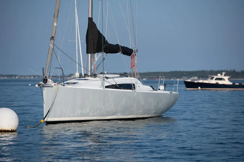 From Away Yacht Photos Pics 2017 Jeanneau SunFast 3200 sailboat anchored on calm water, with distant boats.