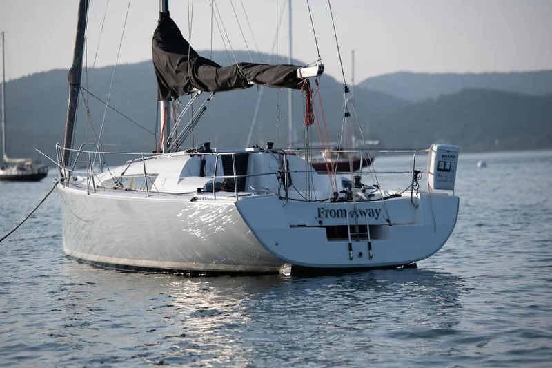 From Away Yacht Photos Pics 2017 Jeanneau SunFast 3200 sailboat anchored on calm water with scenic mountain backdrop.