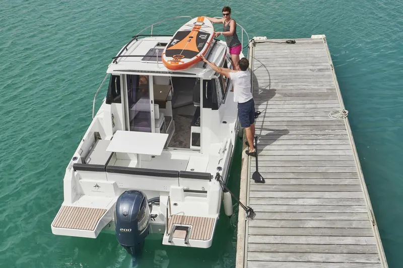  Yacht Photos Pics 2026 Jeanneau NC 795 Series 2 docked, with paddleboard on roof, in turquoise water.