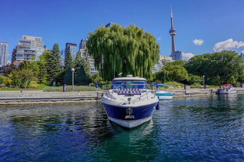  Yacht Photos Pics 2012 Regal 42 Sport Coupe yacht docked near city skyline and lush greenery.
