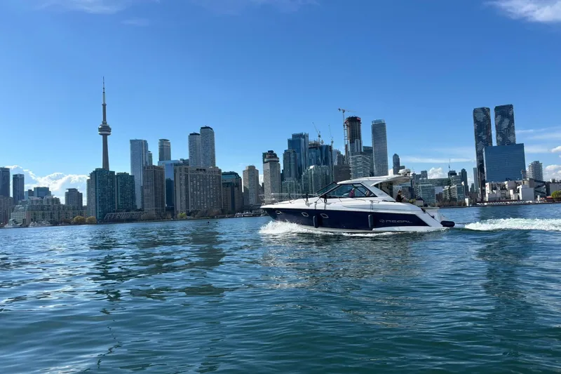  Yacht Photos Pics 2012 Regal 42 Sport Coupe cruising near city skyline on a sunny day.