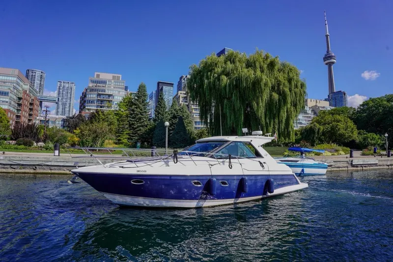  Yacht Photos Pics 2012 Regal 42 Sport Coupe yacht cruising near urban skyline and lush greenery.