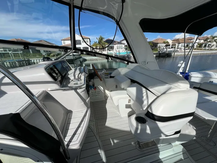 Happy Ours Yacht Photos Pics 2005 Formula 40 PC yacht cockpit with white seating and modern controls, docked by waterfront homes.