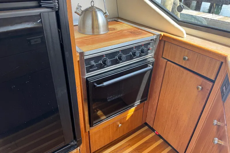Lost Together Yacht Photos Pics 1996 Bayliner 4087 Aft Cabin Motoryacht kitchen with stove, kettle, and wooden cabinetry.