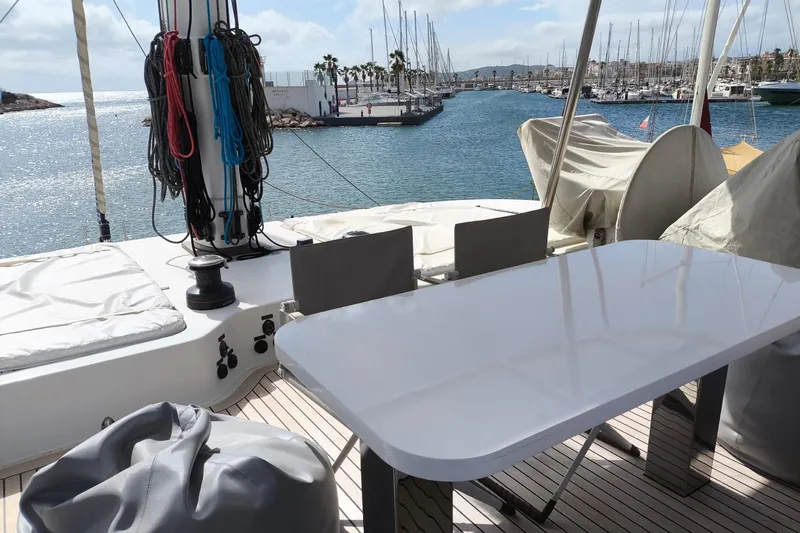 Dolphin Yacht Photos Pics Deck of 2019 Sunreef 50 yacht with table, chairs, and marina view.
