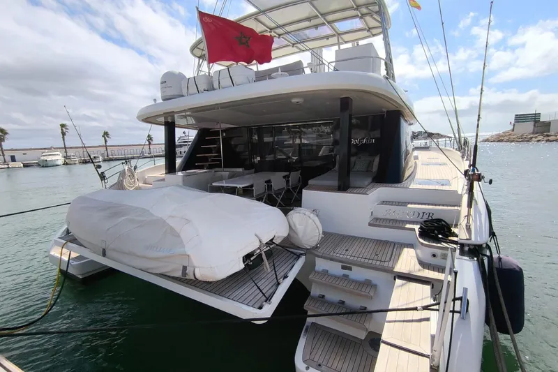 Dolphin Yacht Photos Pics Luxurious 2019 Sunreef 50 yacht docked, featuring spacious deck and Moroccan flag.