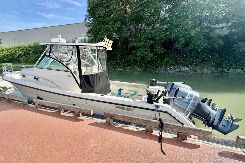  Yacht Photos Pics 2004 Pursuit 2870 Walkaround boat docked by a canal with trees in the background.