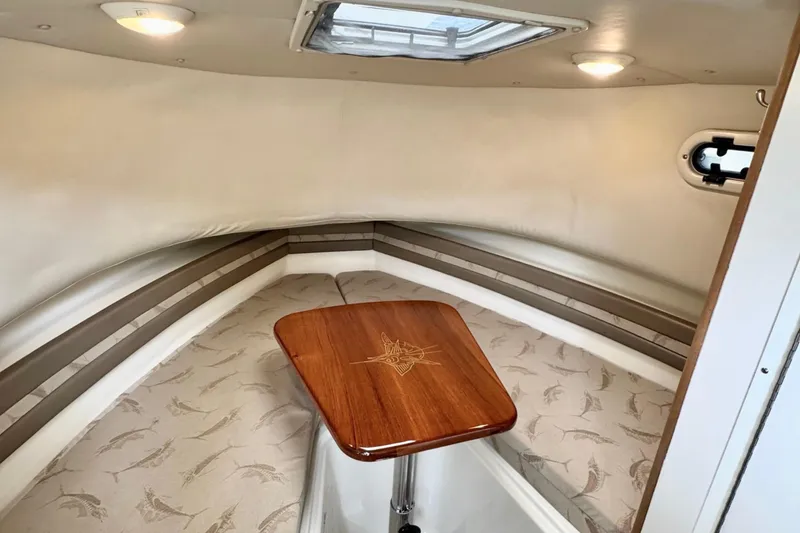  Yacht Photos Pics 2004 Pursuit 2870 Walkaround cabin interior with wooden table and cushioned seating.