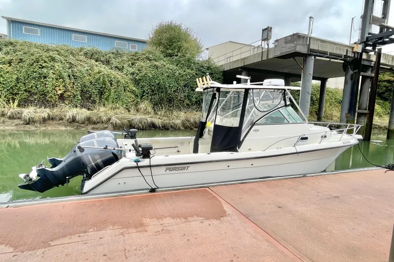  Yacht Photos Pics 2004 Pursuit 2870 Walkaround boat docked by a lush riverside.