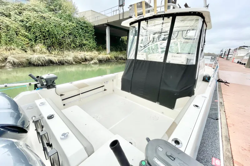  Yacht Photos Pics 2004 Pursuit 2870 Walkaround boat docked by a canal with lush greenery.