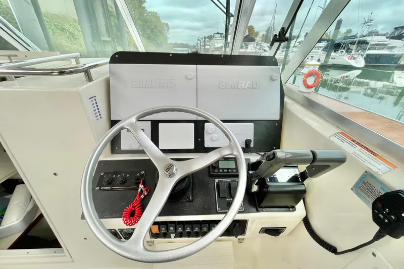  Yacht Photos Pics 2004 Pursuit 2870 Walkaround boat helm with Simrad navigation system and steering wheel.