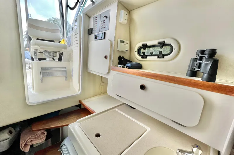  Yacht Photos Pics 2004 Pursuit 2870 Walkaround cabin interior with seating, storage, and binoculars.