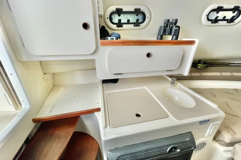  Yacht Photos Pics 2004 Pursuit 2870 Walkaround cabin interior with sink, storage, and portholes.